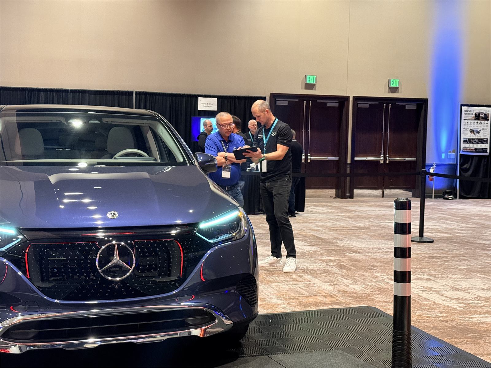 Technicians reviewing inspection results on a tablet beside a luxury SUV